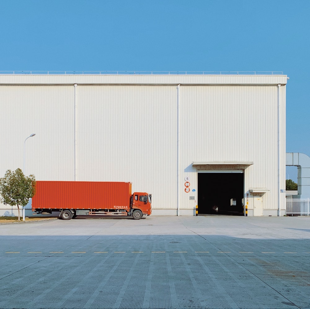 A red truck parked outside a warehouse 