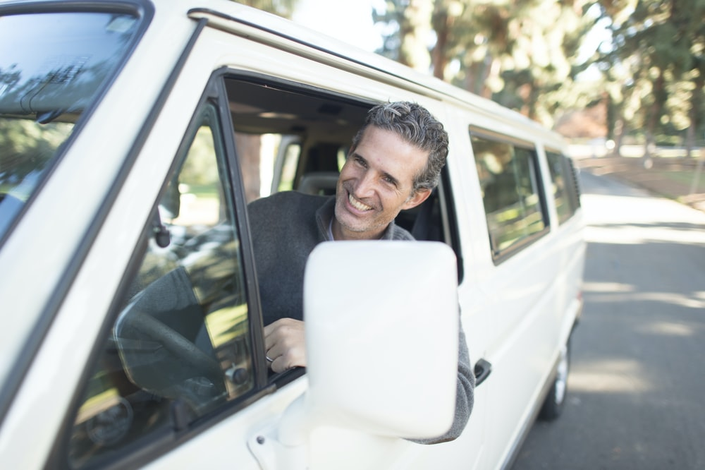 a driver smiling as he drives a van